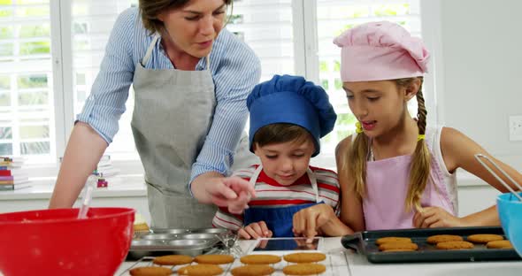 Mother and children making cookies in kitchen alt