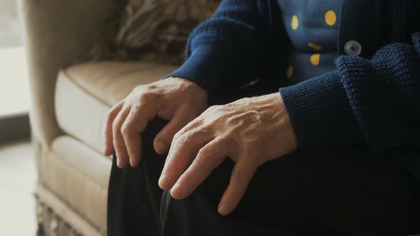 Close-up shot of mature worry woman moving hands and fingers on the knees. Stressed unhappy people a