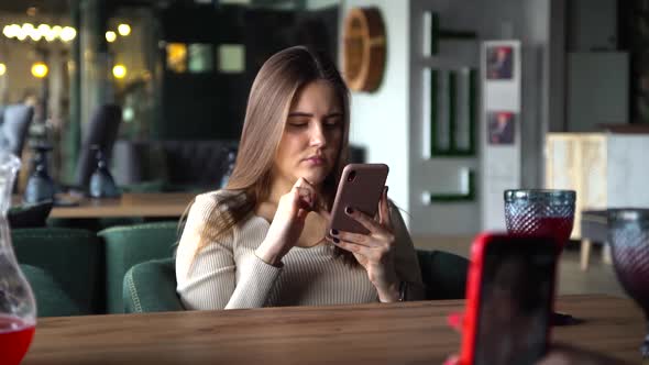Girl Sitting in Coffee Shop Playing Mobile Phone for Social Media on Vacation Time