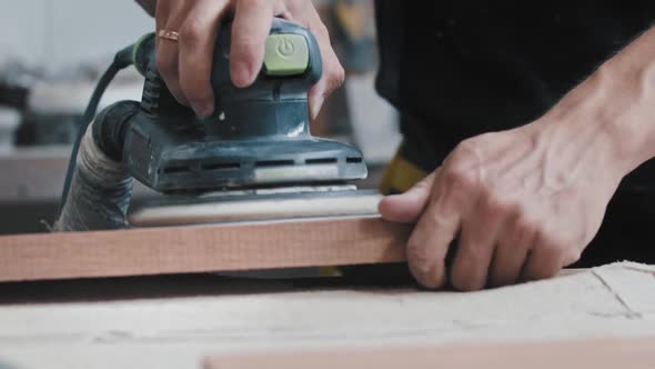 The Worker Grinding Tne Flat Surface of a Wooden Detail on the Table alt