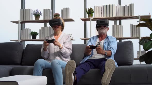 Senior couple playing a video game with joysticks and having fun with virtual reality glasses