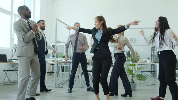 Attractive Girl in Suit Dancing with Colleagues Relaxing at Corporate Party Celebrating Event alt