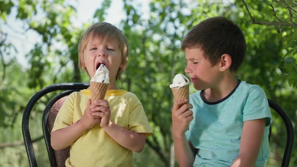 Sweets Little Boys Enjoy Eating Delicious Cool Ice Cream on a Hot Summer Day Sitting on Chairs alt