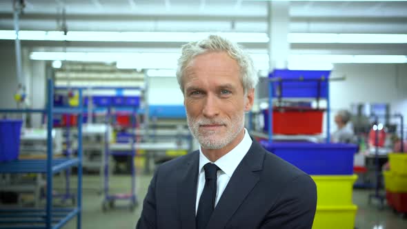 Serious manager in factory looking to camera and smiling alt