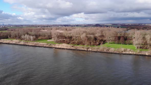 Autumnal Trees At The Embankment Of Oude Maas In Puttershoek, Netherlands On A Sunny Day. aerial alt