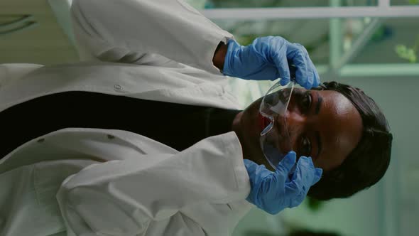 Vertical Video Portrait of African Biologist in White Coat Looking Into Camera alt