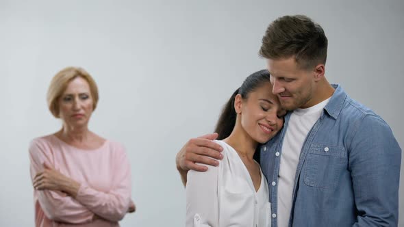Offended Mother-In-Law Looking at Couple Tenderly Hugging, Lack of Attention alt