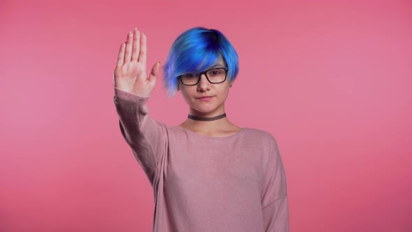 Young Unusual Girl with Blue Hair Making Stop Palm Gesture Over Pink Studio alt