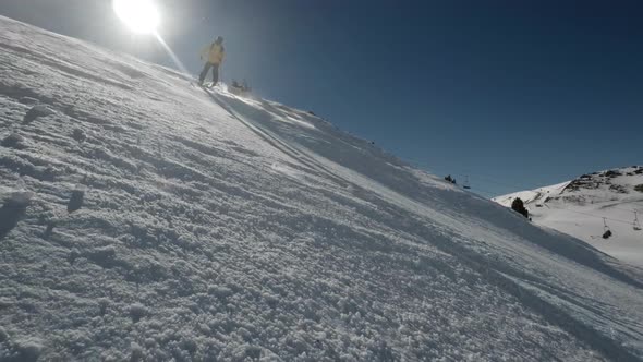 Skier going downhill while sprays snow in slow motion carving down the slope on a sunny day alt