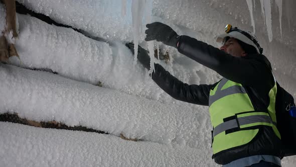 Curios Caucasian Bearded Man Breaking Icicle on Winter Night Outdoors alt