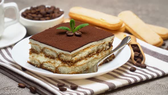 Portion of Traditional Italian Tiramisu dessert, cup of espresso and coffee beans alt
