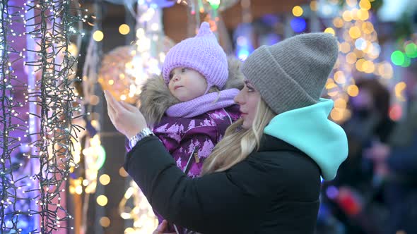 Happy mom and her little daughter choose holiday decorations at the street Christmas market