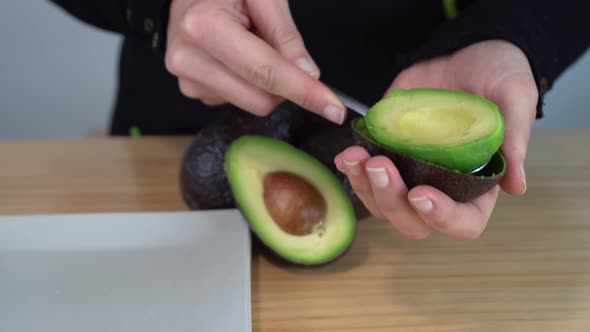 Young woman dropping a green avocado on a plate