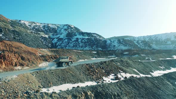 Loaded Truck is Riding Along Snowy Roads of a Mine Site alt