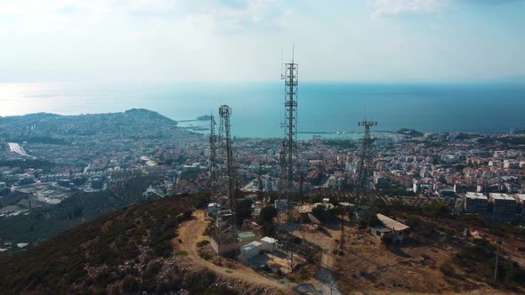 Communication towers are located on a mountain near the sea city. alt