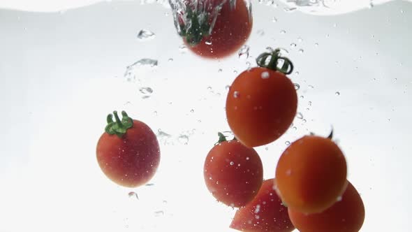 Closeup of Fresh and Health Cherry Tomatoes Falling Into Clear Water with Big Splash on Black alt