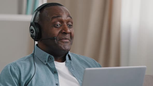 Closeup Adult African American Man in Headphones Communicating on Webcam on Laptop Using Video alt