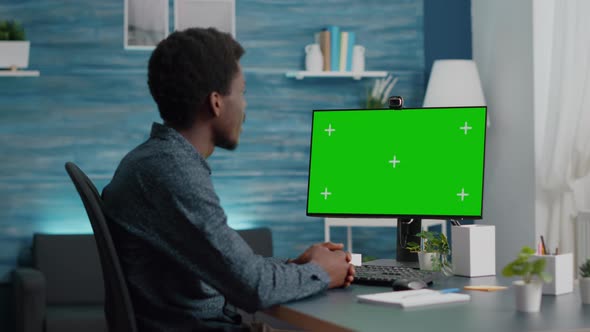 Wide Shot of African American Man Talking on Video Call on Computer with Mock Up Chroma Display alt