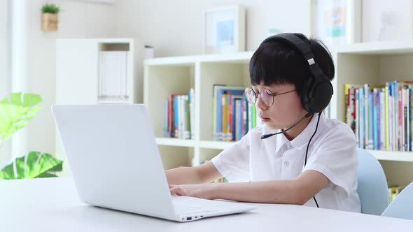 Young student wearing wireless headphones and taking online class on laptop alt