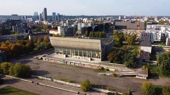 Modern Vilnius downtown and derelict building of Concert and Palace Hall, aerial descend view alt