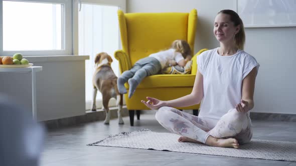 Mother Meditates Near Playing Daughter and Dog