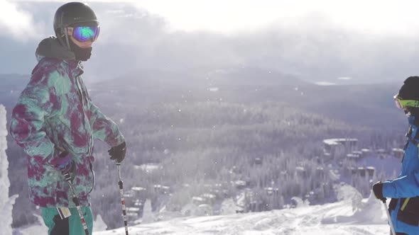 Two skiers admiring the view from a snow-covered mountain. alt