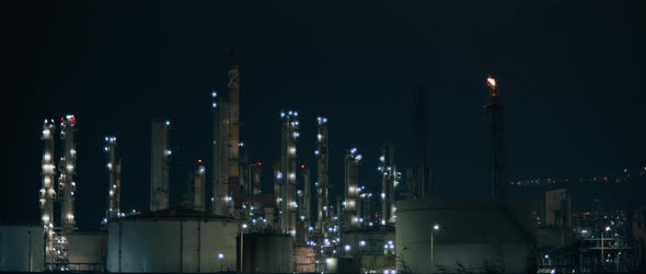 Power plant with lights lit up at night and fire smoke coming out of chimney alt