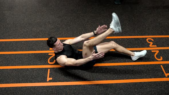 Sportsman Man in Sportswear Doing Raisedleg Situp and Clap Exercises on Gym Floor Exercising