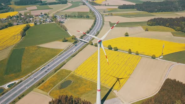 Yellow Rapeseed Field Panorama with Wind Turbine or Wind Wheels Along the Highway