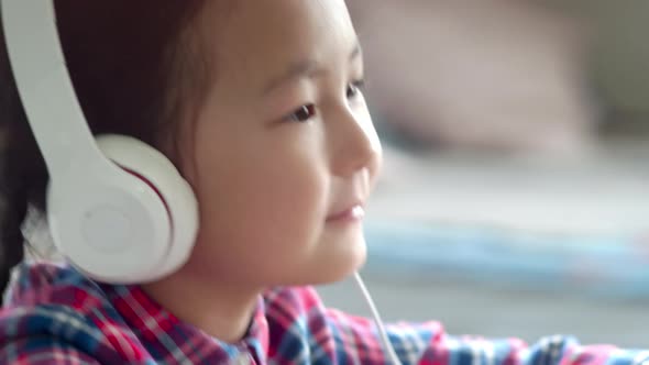 Little Asian Girl in Headphones Moving to Music on Smartphone