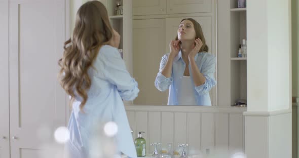 Woman looking into mirror and applying make-up