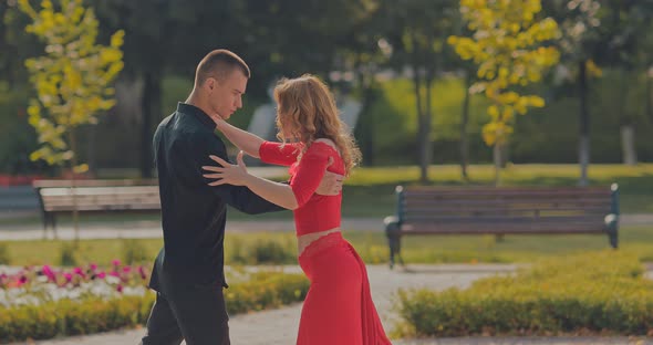 Beautiful Young Dancer with a Partner Dances Tango in a Summer Park