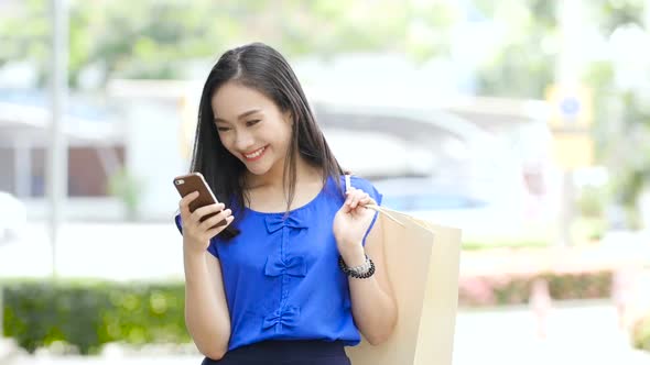 Girl holding shopping bag and looking at mobile screen
