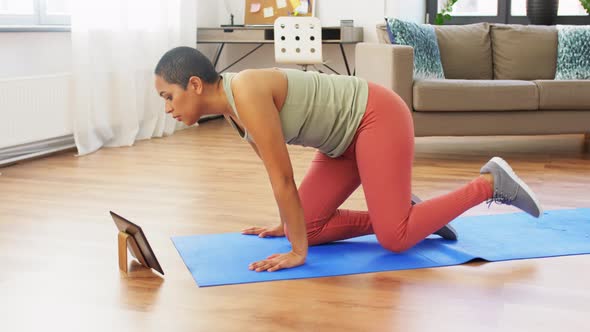 Woman with Tablet Pc Doing Yoga Child Pose at Home alt