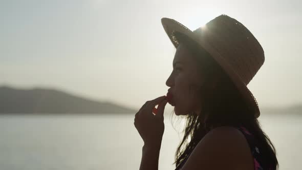 A Girl Bites a Strawberry at Sunset Near the Sea alt