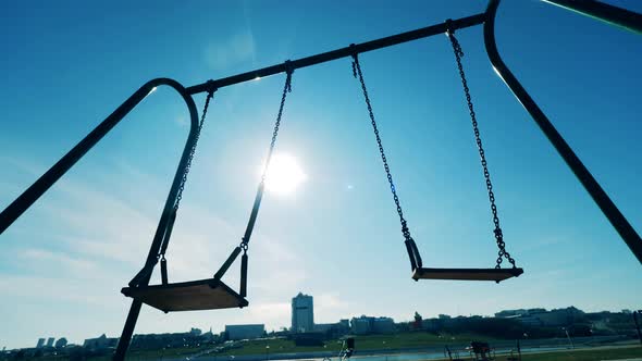 The Sun Shining Through the Swings in Motion. Covid-19 Outbreak, Coronavirus Lockdown Concept. alt