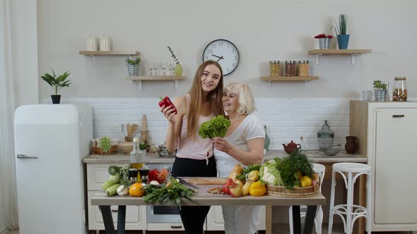 Mature Woman with Grandchild Girl Recommending Eating Raw Vegetable Food. World Vegan Day Concept alt