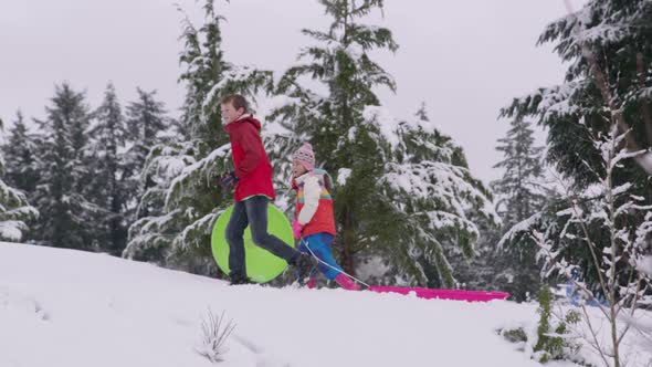 Kids walking through snow with sleds in winter