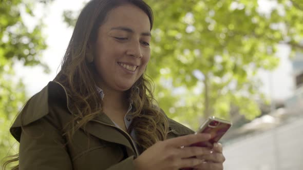 Smiling Young Woman Holding Modern Smartphone Outdoor alt