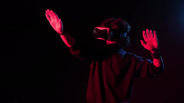 Man with VR Helmet on His Head Playing in Redblue Lights Online Party alt