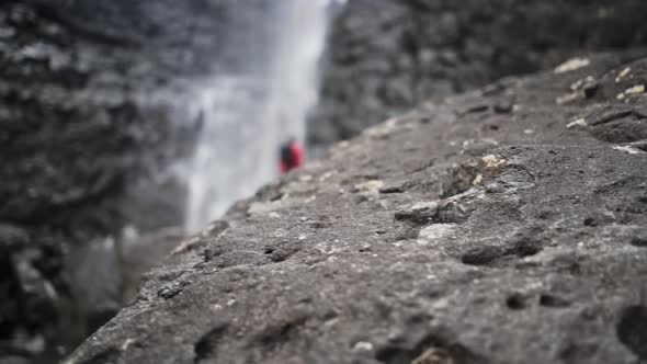 Man On Rocks Under Fossa Waterfall From Cliff alt