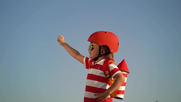 Kid having fun with toy paper wings against summer sky background