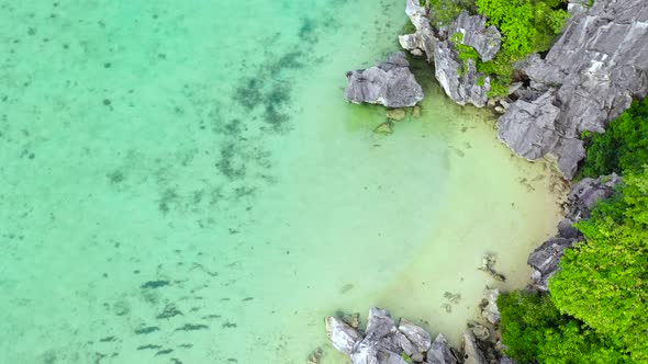 Tropical Island with a White Beach and Limestone Cliffs Aerial View alt