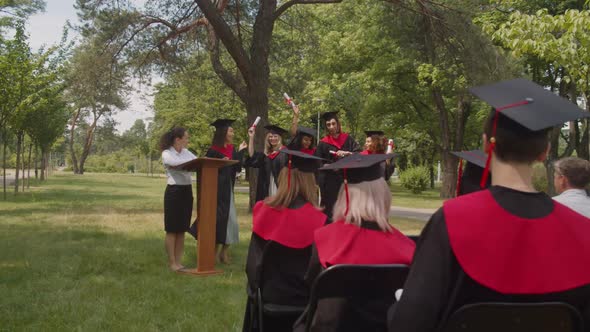 Carefree Diverse Multiethnic Graduates with Diplomas Dancing at Graduation Day alt