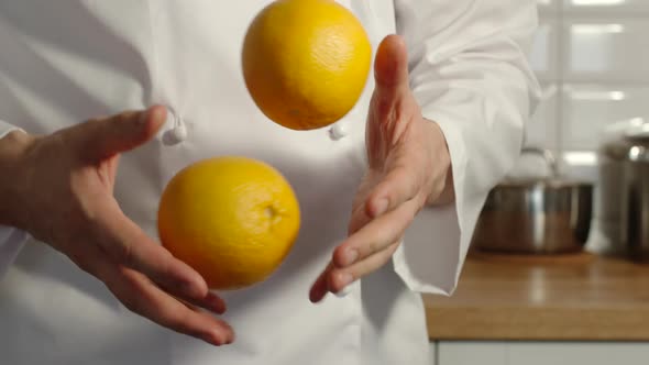 Chief-cooker juggles an oranges in a kitchen