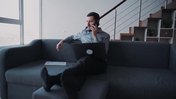 Handsome Man Is Sitting on Couch Listening and Checking New Information About Business