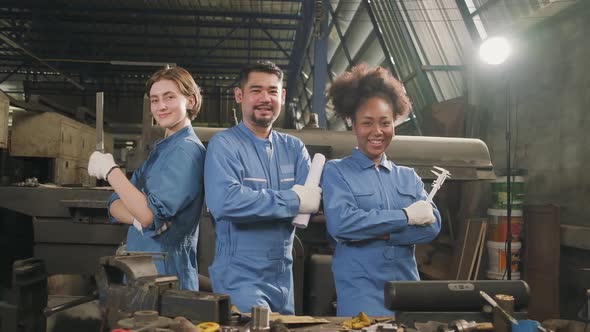 Multiracial workers collaborate and express happy work in a mechanical factory. alt