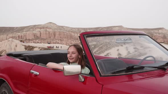 Young Pretty Girl Sit in Passenger Seat in Red Retro Convertible Car Looking Around Enjoying