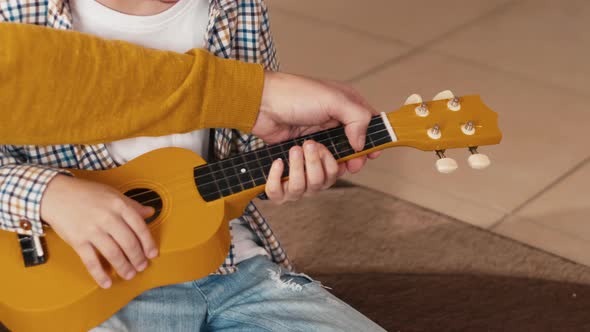 Dad helping son to play guitar