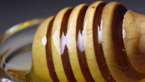 fresh golden honey pours beautifully from a wooden honey spoon alt